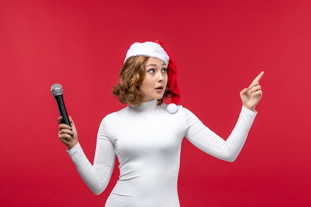 Бесплатное фото Вид спереди молодой женщины, держащей микрофон на красном