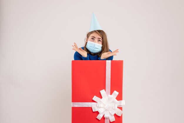 無料写真 白い壁の上のマスクのプレゼントボックス内の若い女性の正面図