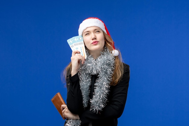 Бесплатное фото Вид спереди молодой женщины с билетами на самолет на синей стене