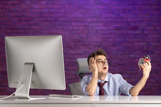 Front view office worker behind office desk holding clocks