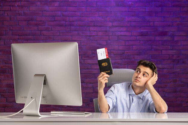Офисный работник вид спереди сидит за своим рабочим местом с паспортом и билетами