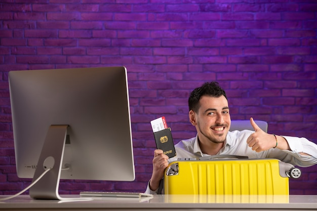 Front view office worker sitting behind his working place with tickets passport and bag