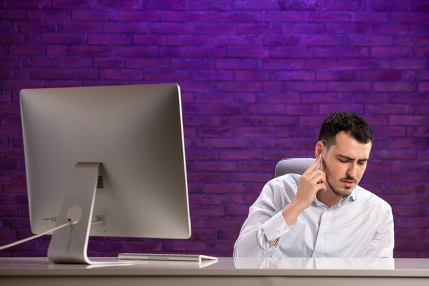 Front view office worker sitting behind his working place