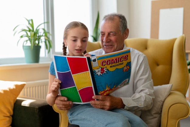 Free photo front view old man and girl reading comics