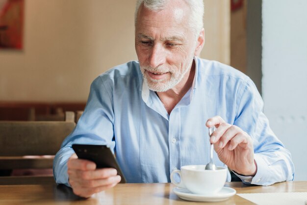 Front view old man looking at his phone