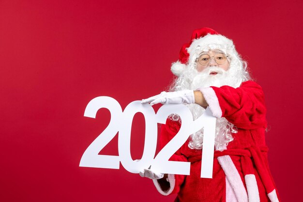 Free photo front view of old santa claus holding writing on red wall