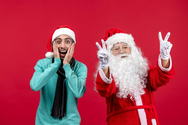 Front view of old santa claus with man standing on red wall