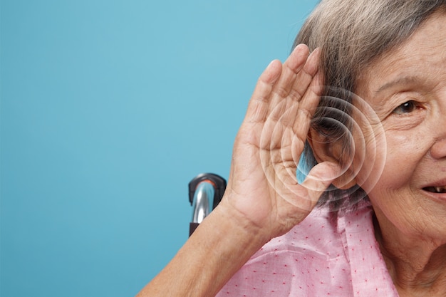 Пожилая женщина, вид спереди, испытывает проблемы со слухом