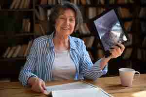 Foto gratuita donna anziana di vista frontale in biblioteca