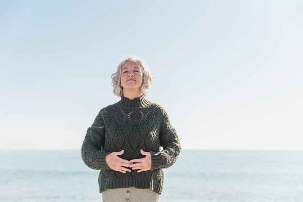 Front view old woman with closed eyes on the beach