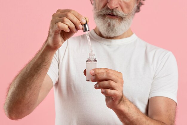 Front view of older bearded man using serum