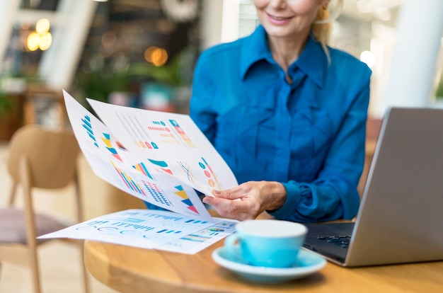 Free photo front view of older business woman dealing with papers while having coffee