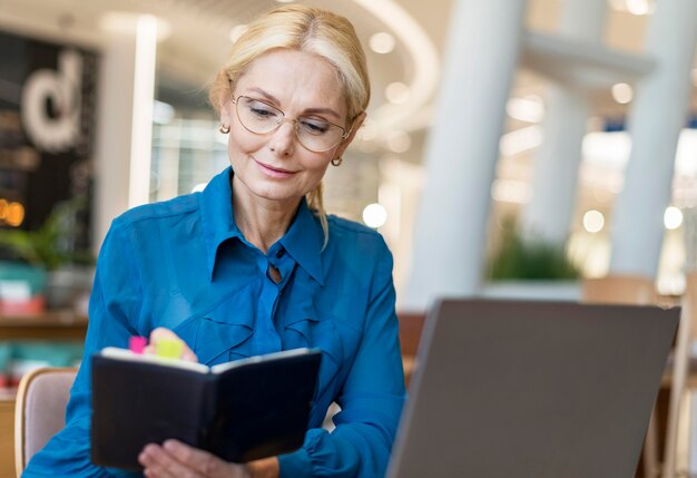 Front view of older business woman with glasses writing in agenda