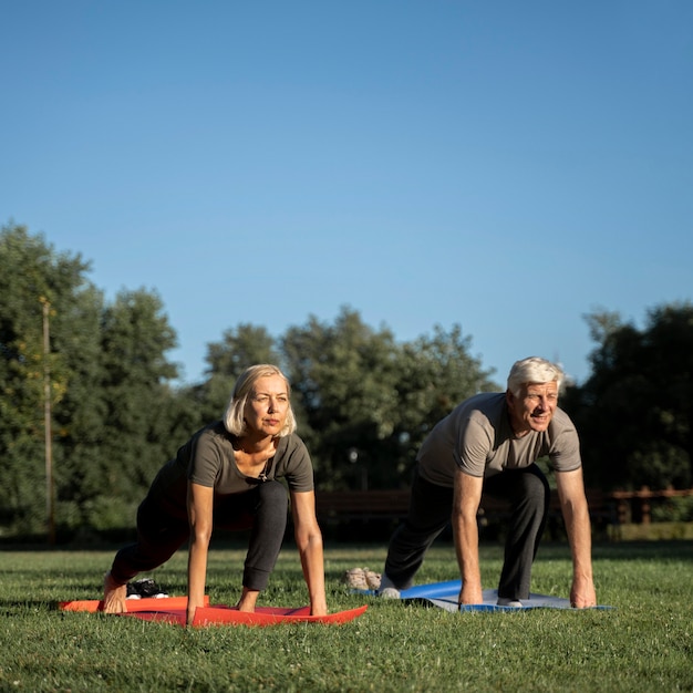 Free photo front view of older couple doing yoga outside