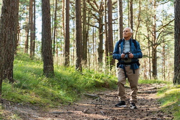 Front view of older man exploring nature outdoors with backpack