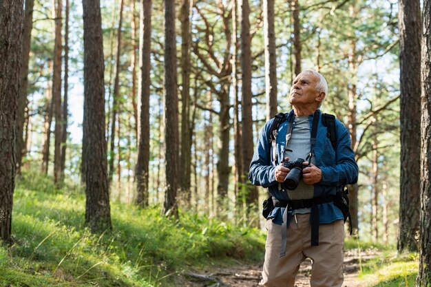 Front view of older man with backpack exploring nature