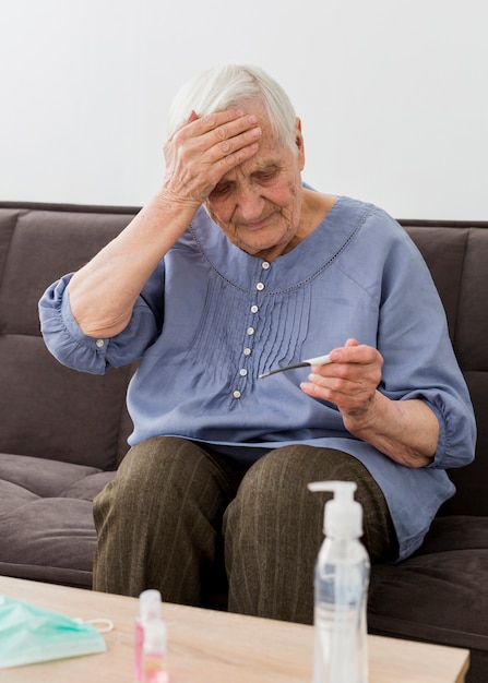 Free photo front view of older woman checking her thermometer