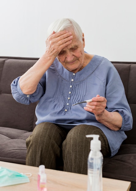 Front view of older woman checking her thermometer
