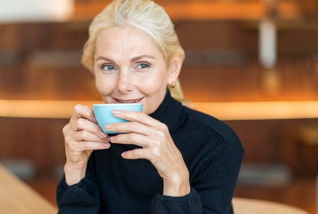 Front view of older woman having cup of coffee while working