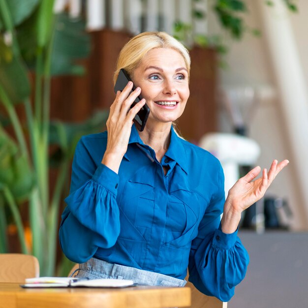 Front view of older woman talking on the phone while working