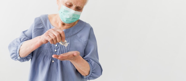 Free photo front view of older woman using hand sanitizer with copy space