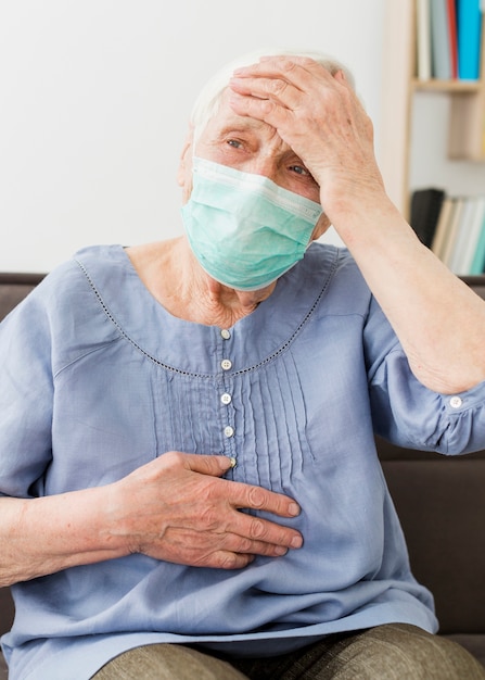 Front view of older woman with medical mask feeling ill