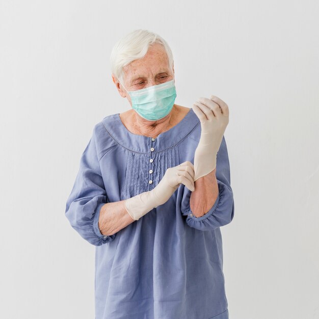 Front view of older woman with medical mask and surgical gloves