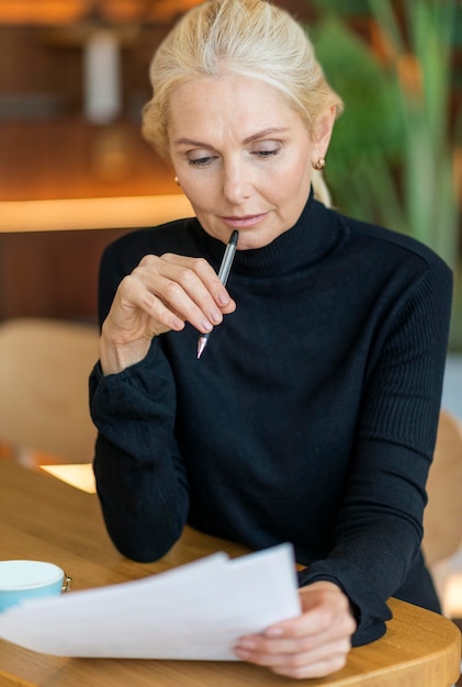 Front view of older woman at work reading papers and thinking