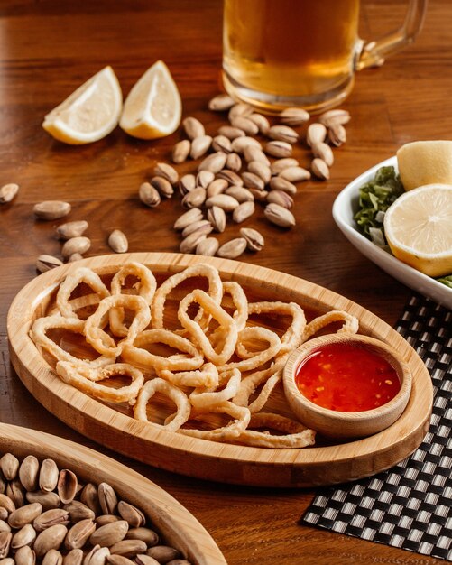 갈색 나무 테이블 스낵 식품 식사에 맥주 땅콩 소스와 함께 전면보기 양파 링