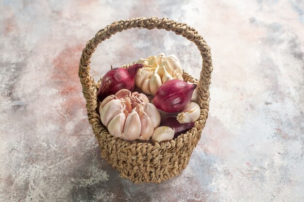 Front view onions and garlics fresh ingredients inside designed basket