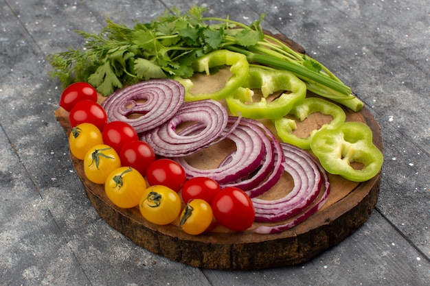 front view onions tomatoes pepper sliced and whole on the brow desk and grey