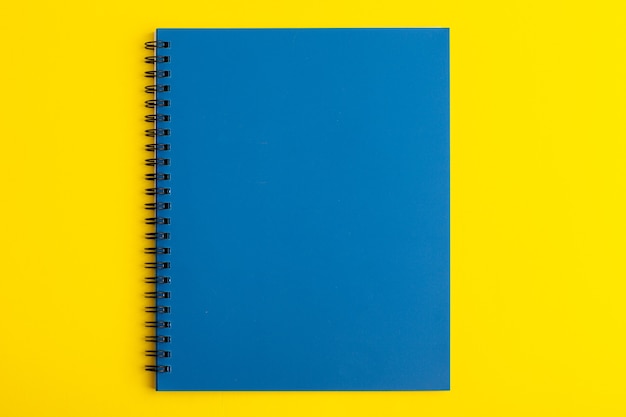 Вид спереди открытая синяя тетрадь на желтом столе