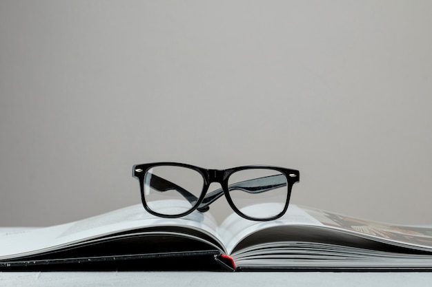 Free photo front view open book with glasses