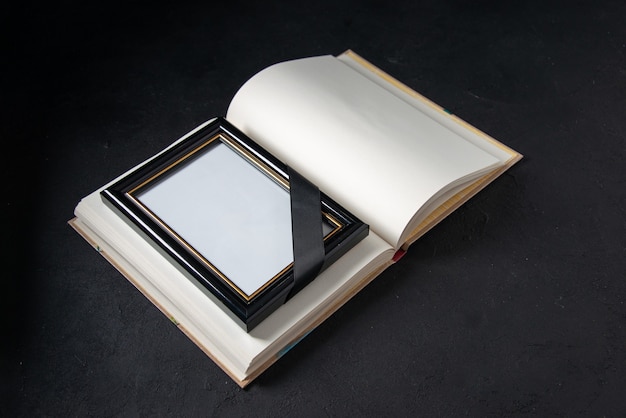 Вид спереди открытой книги с картинной рамкой на черном