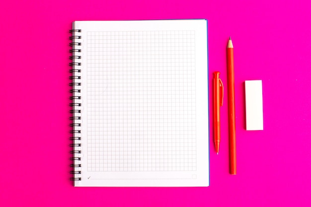 Вид спереди открытая тетрадь с ручкой и карандашами на фиолетовой поверхности