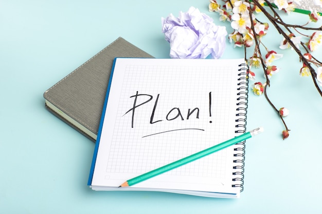 Front view open copybook with pencil and flowers on blue surface