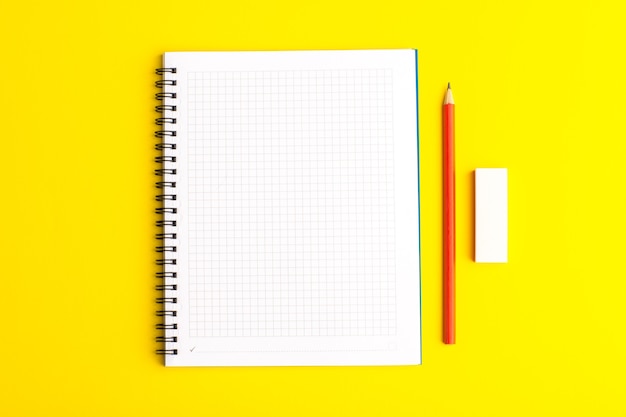 Вид спереди открытая тетрадь с карандашом на желтой поверхности