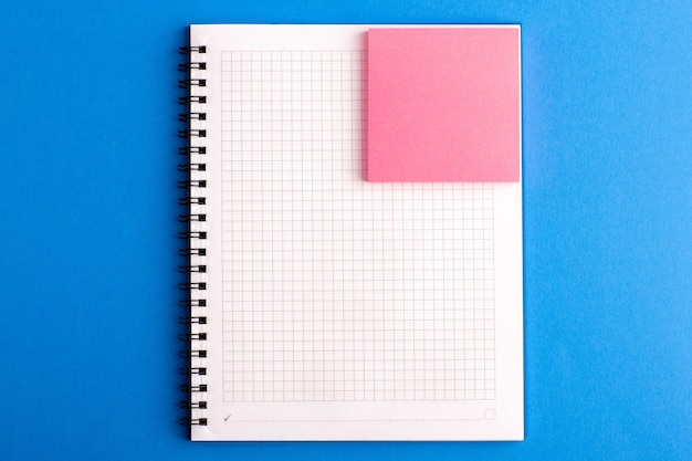 Front view open copybook with pink sticker on the blue desk