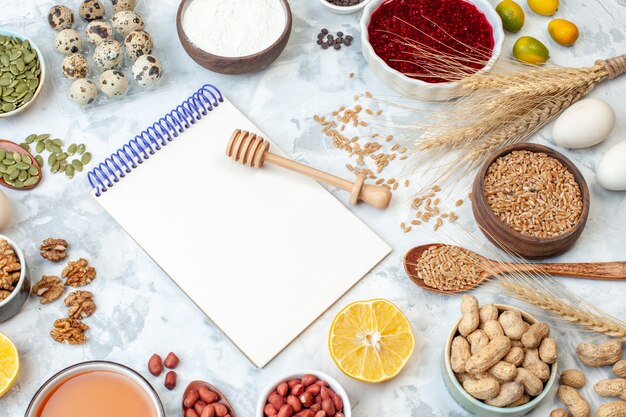 Front view open notepad with eggs flour jelly different nuts and seeds on white background nut color cake sweet pie photo sugar dough