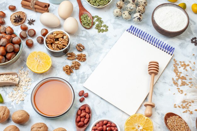 Front view open notepad with eggs flour jelly different nuts and seeds on white background nut dough color cake sweet pie photo sugar