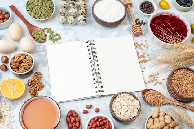 Front view open notepad with jelly eggs different nuts and seeds on white background dough color cake sweet sugar pie nut heart photo