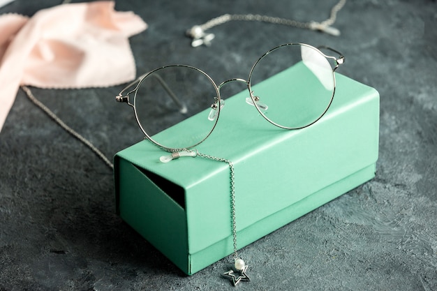 청록색 선글라스 상자와 실버 팔찌 고립 된 시력 눈을 가진 회색 책상에 전면보기 광학 선글라스
