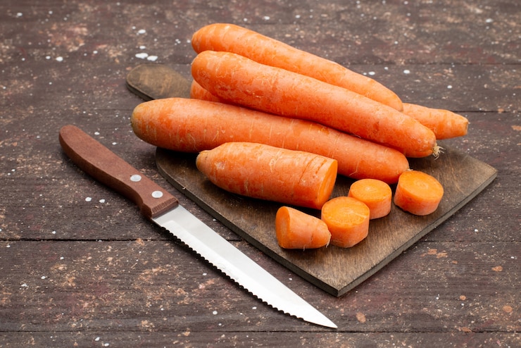 Front view orange carrots sliced and whole on brown