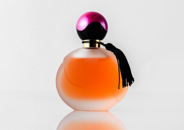 A front view orange designed perfume with black and purple cap isolated on the white floor