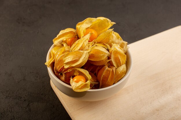 A front view orange fruits inside peels and white plate on wooden desk and dark