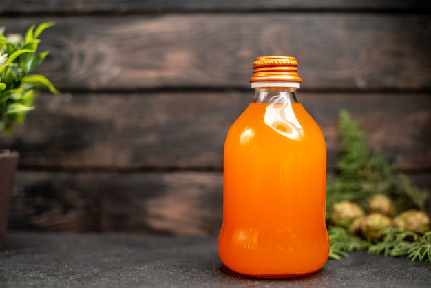 Апельсиновый сок, вид спереди в бутылке, свежие апельсины на коричневой изолированной поверхности