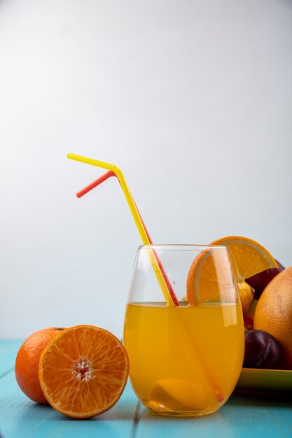 Front view orange juice in a glass with straws and oranges