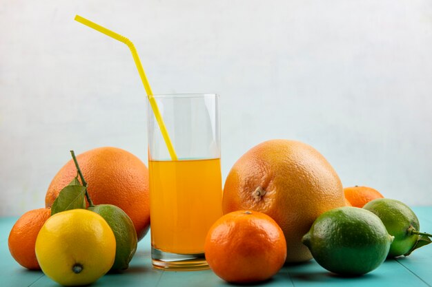 Front view orange juice in a glass and yellow straw with oranges  grapefruit and lemon with lime