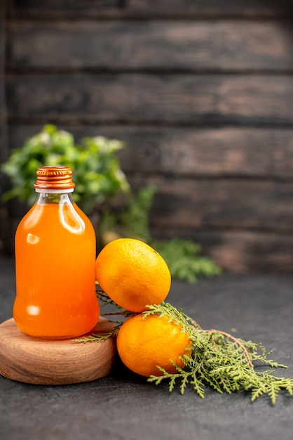 Апельсиновый сок, вид спереди на деревянной сервировочной доске, свежие апельсины, комнатные растения на коричневой изолированной поверхности