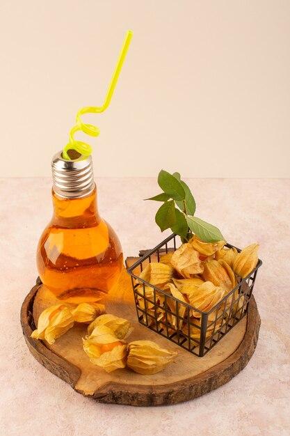 A front view orange peeled physalises inside basket with cocktail on the pink desk 